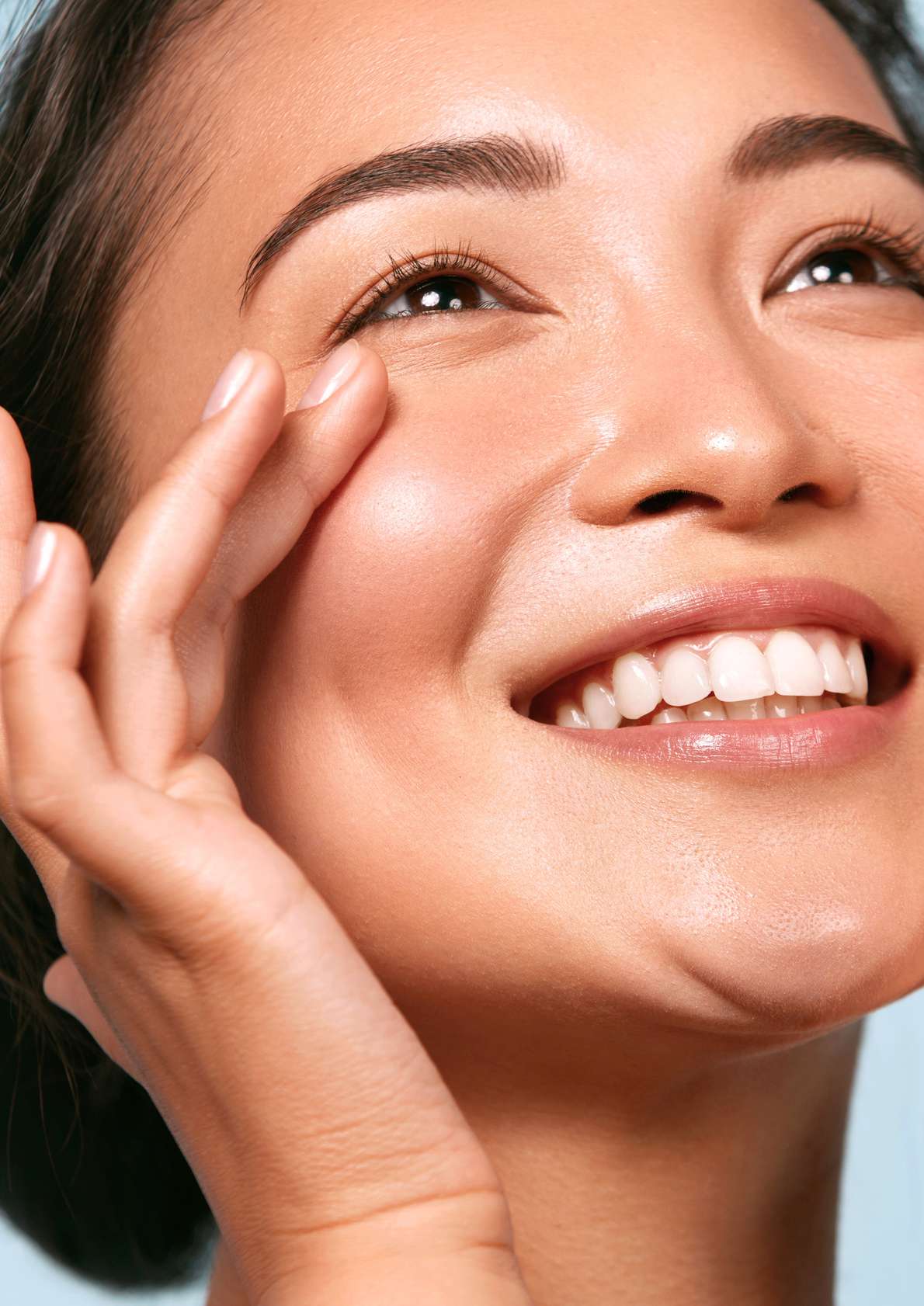 A smiling woman touching her cheek